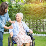 A carer walking with a resident through the garden of an aged care home