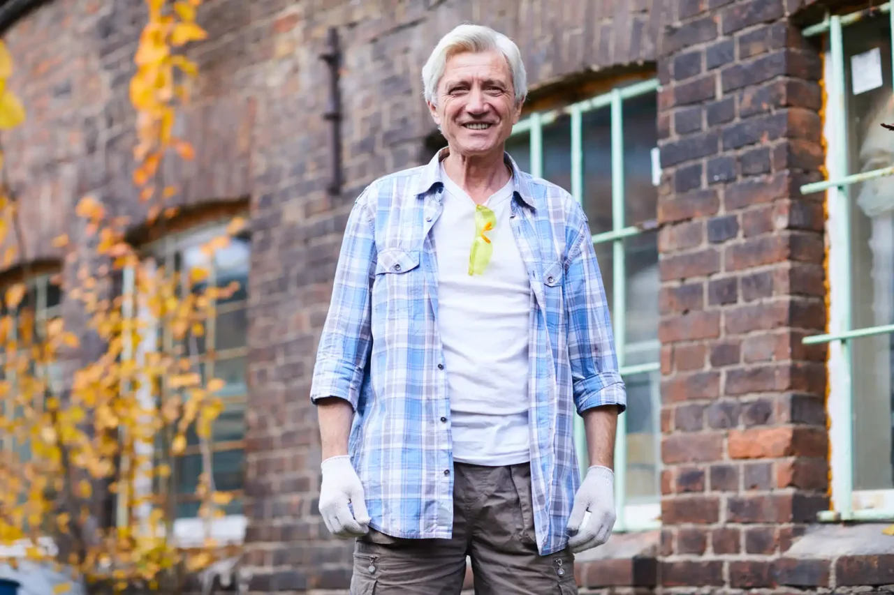 64aa3ead33e313482da52d955bb9cd8853c1a307 A contractor standing outside a brick apartment block