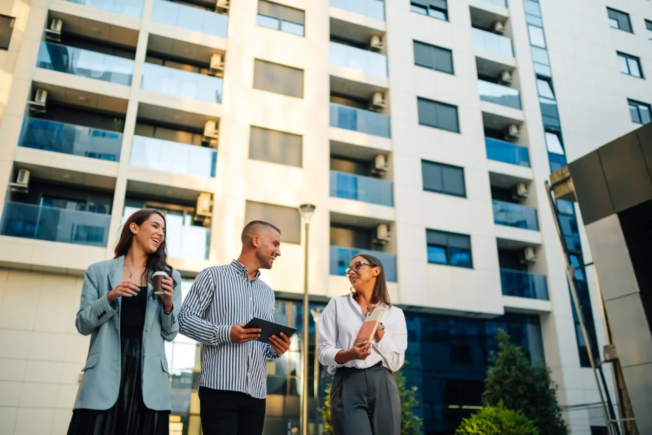 afa37b28fb29a824156d36e47e54ef1cfcd7a262 Three people talking outside a modern apartment building