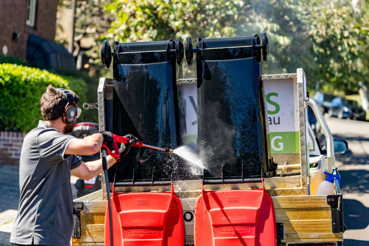 ddb3994c2dc869ff7aaa0ad213cd8c5b7068f736 myBins operator pressure-washing wheelie bins on the truck